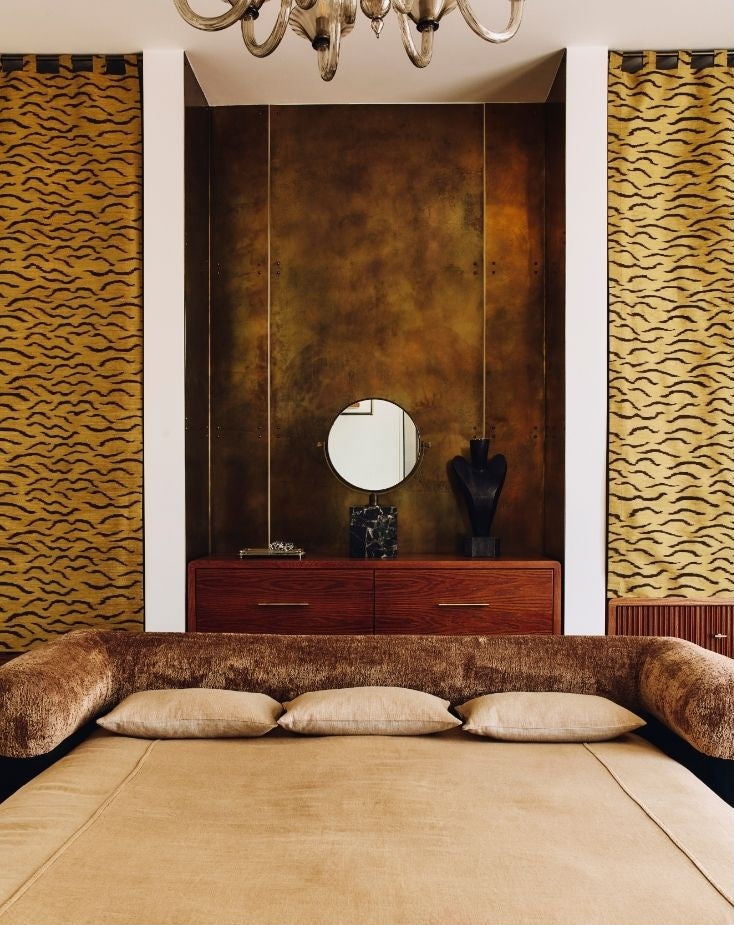Bedroom with patinated bronze wall panels and tiger-stripe curtains showcasing Tala Fustok Studio pieces