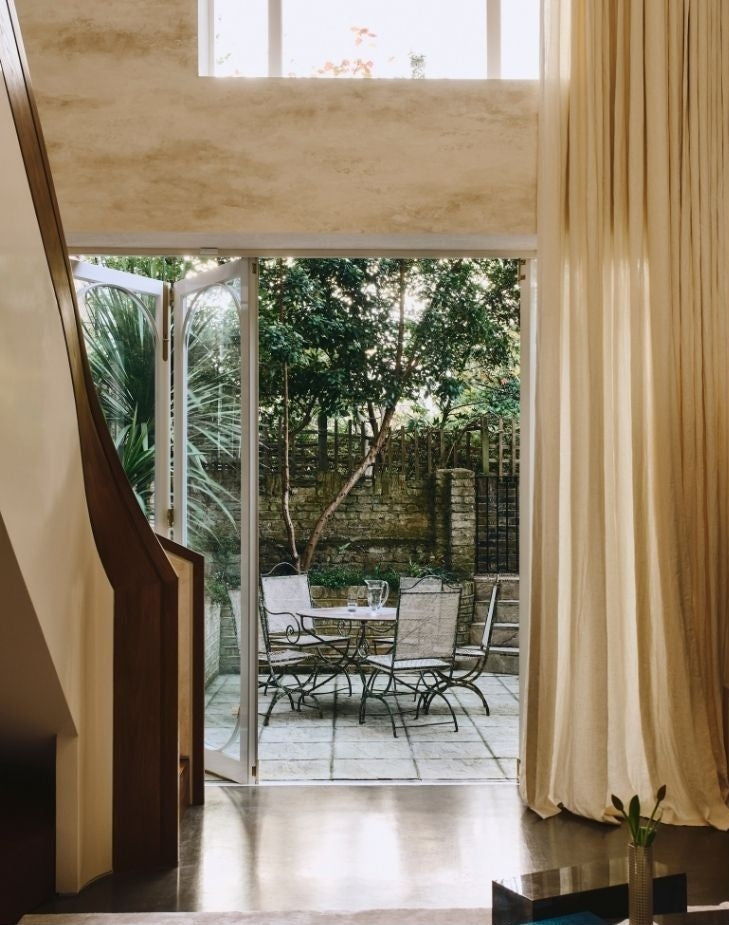 Interior opening to a stone patio and lush garden from a Tala Fustok Studio project