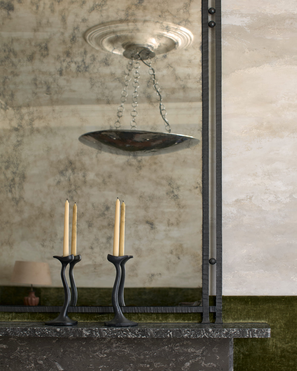 Close view of Gaze’s antiqued mirror, reflecting a pendant light and two candle holders