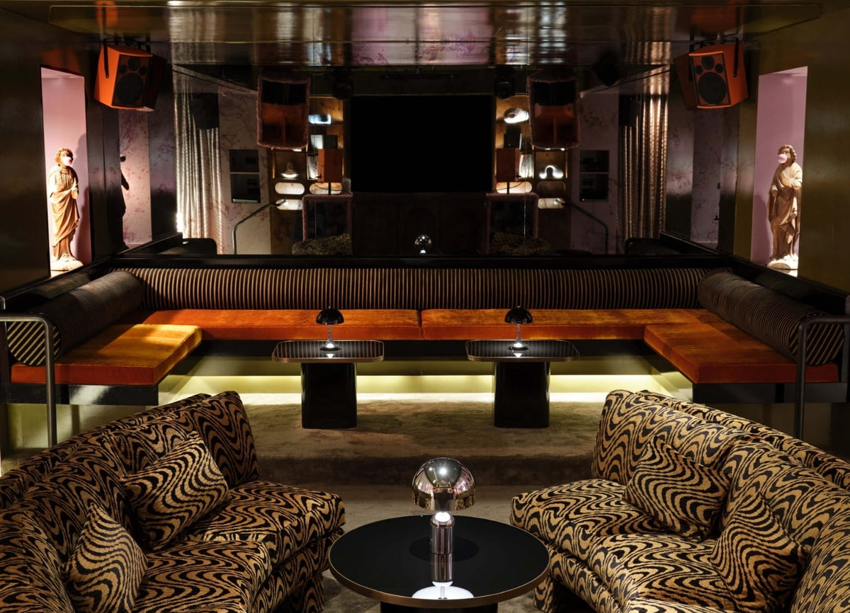 Lounge with orange velvet banquette, tiger-stripe chairs, and bubblegum statues at CoOc Members Club