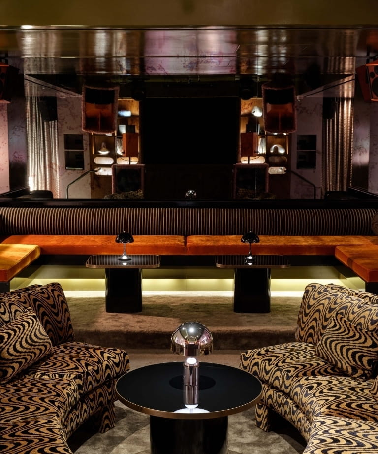 Mirrored lounge with tiger-stripe armchairs and an orange velvet banquette at CoOc Members Club