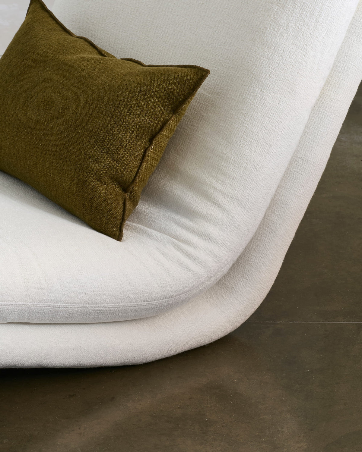 Close-up of Path’s cream upholstery and olive cushion along the curved seat