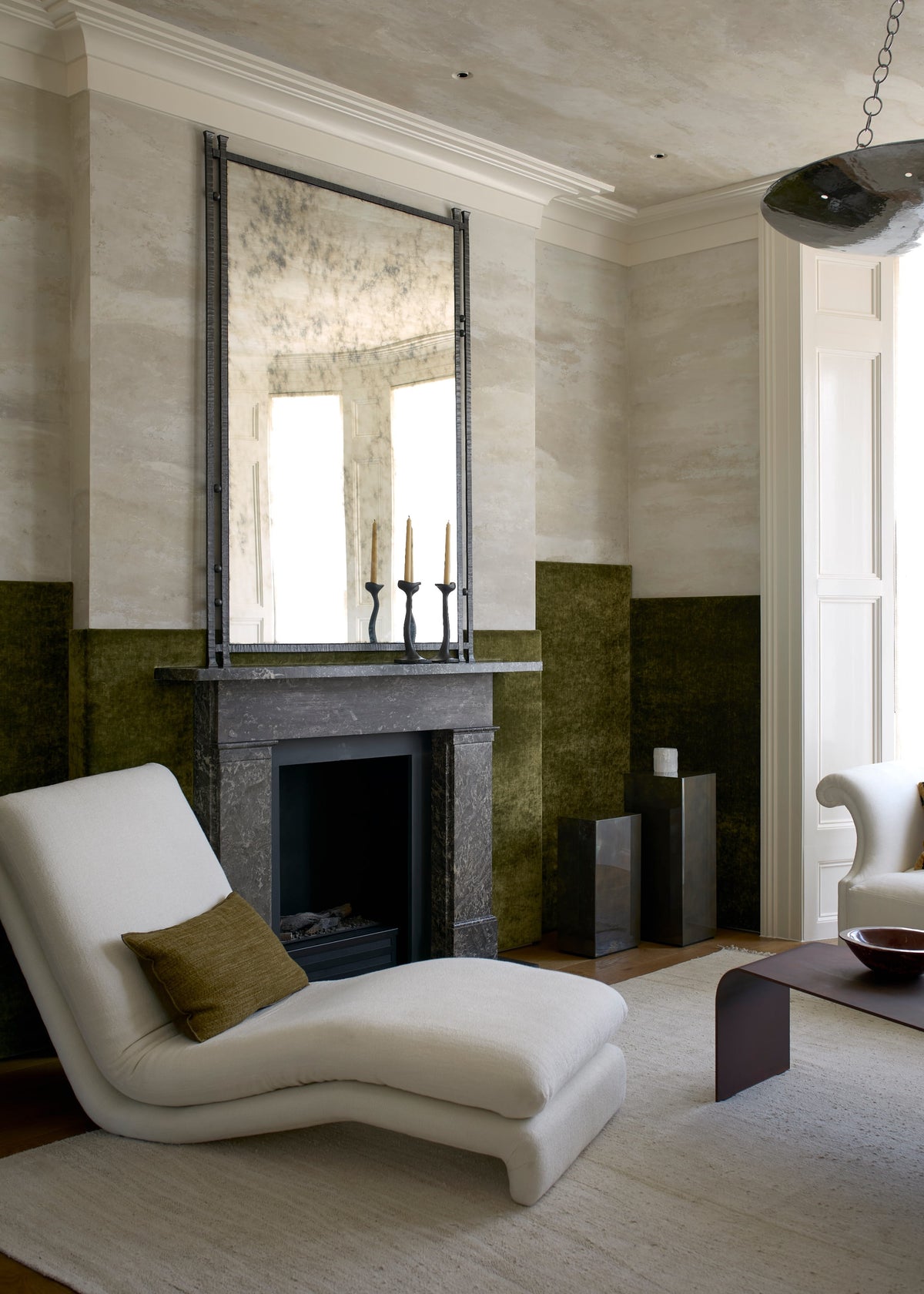 Path chaise in a room with a marble fireplace, olive wall panels, and a dark coffee table