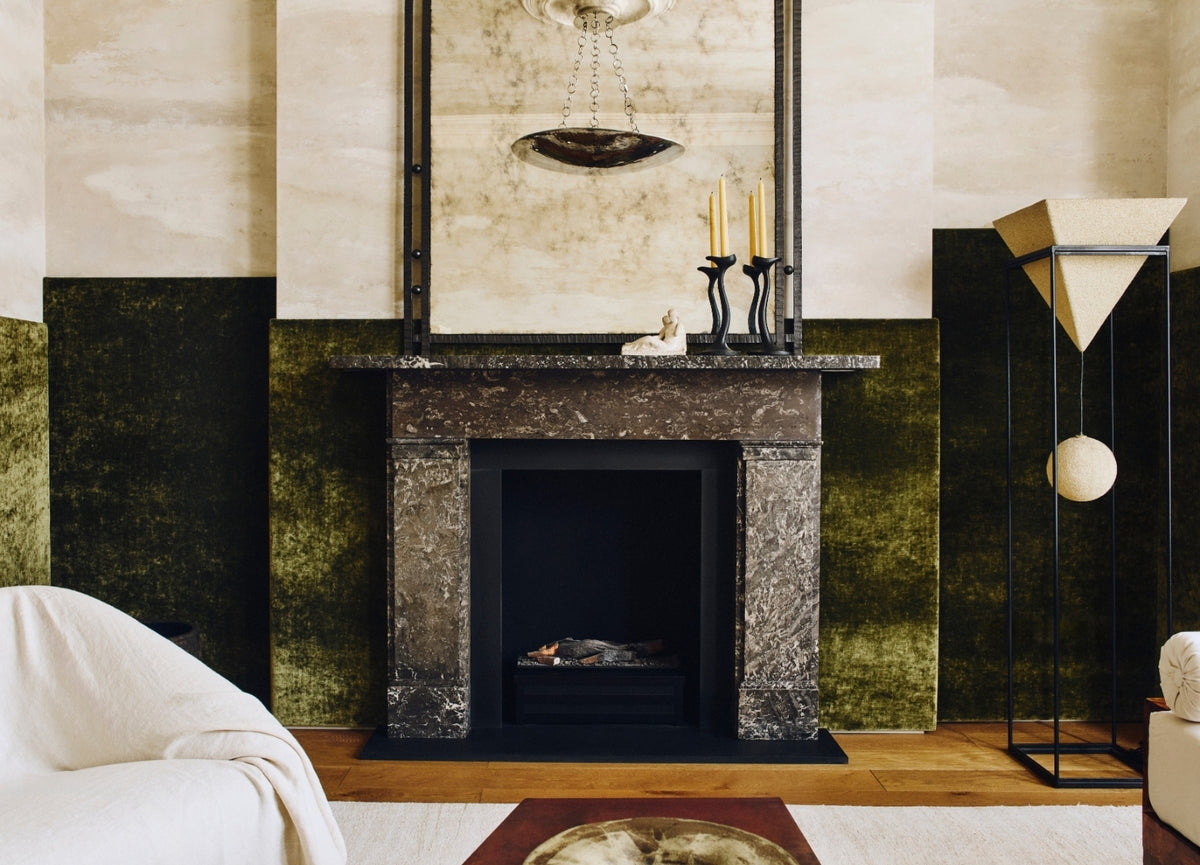 Olive velvet living room with a dark marble fireplace and antiqued mirror in the Ladbroke Grove apartment