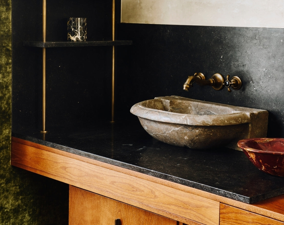 Bathroom vanity with a stone vessel sink, bronze taps, and olive velvet in the Ladbroke Grove apartment