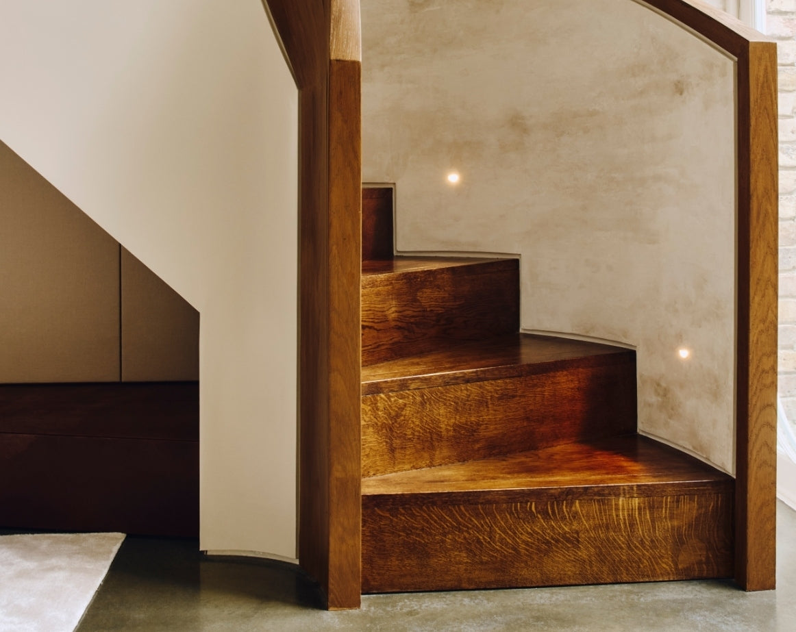 Curved timber staircase with recessed wall lights in the Ladbroke Grove apartment by Tala Fustok Studio