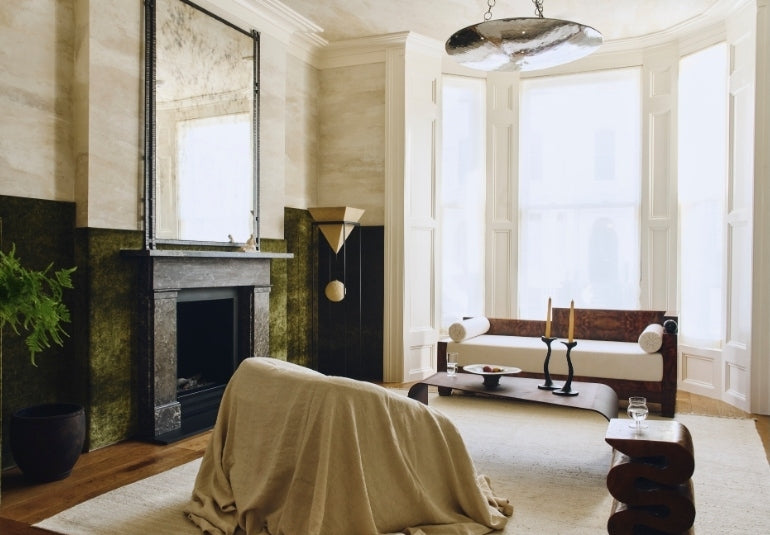 Bay-window living room with a burl-wood daybed and marble fireplace in the Ladbroke Grove apartment