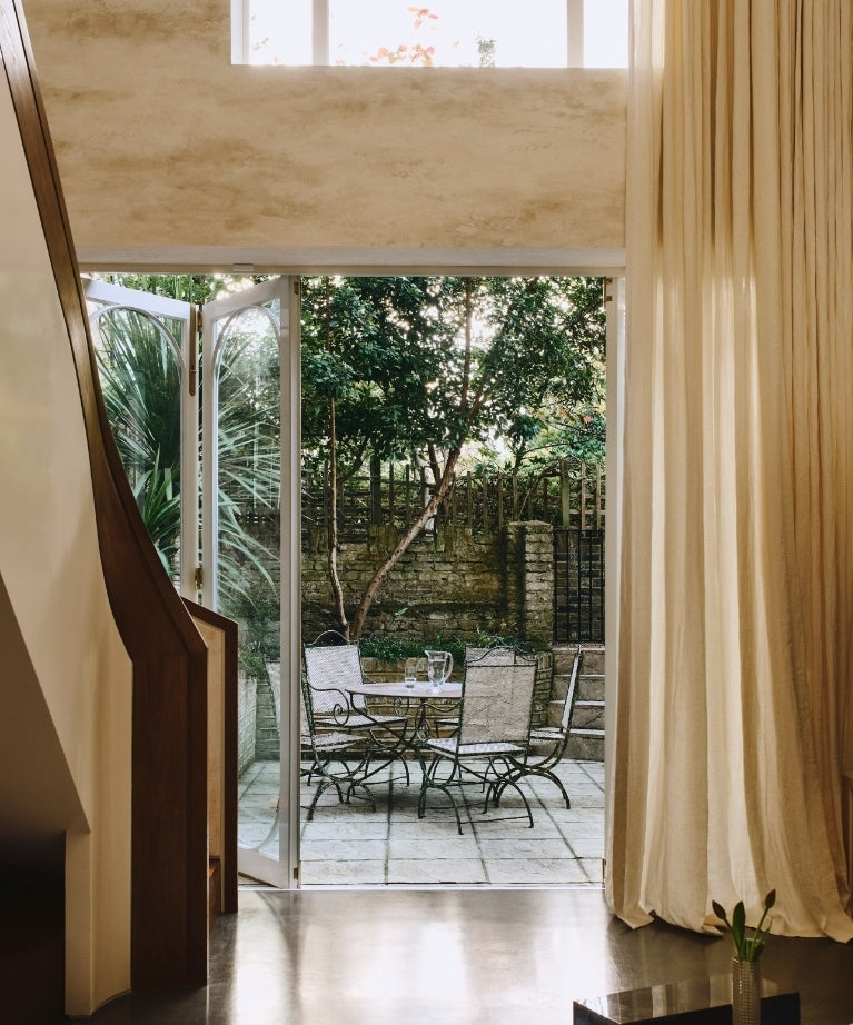 Interior opening to a stone patio and garden from the Ladbroke Grove apartment by Tala Fustok Studio