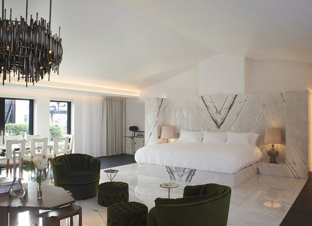 Suite with a book-matched marble headboard and green velvet chairs at The Mandrake Hotel