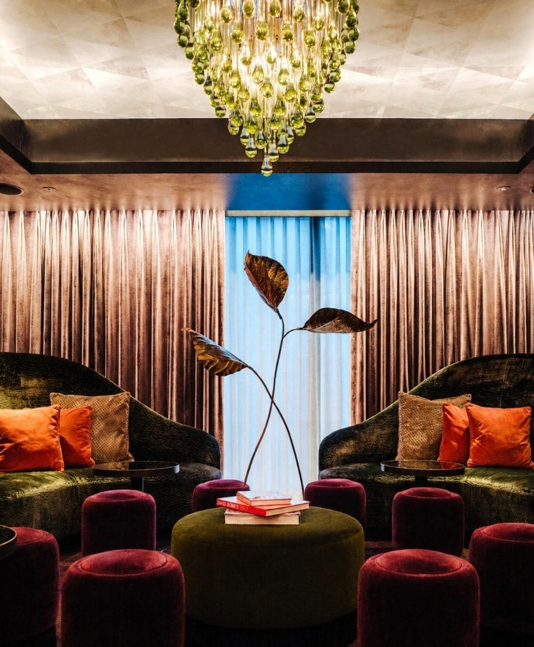 Green velvet lounge with a lime glass chandelier and champagne drapery at The Mandrake Hotel