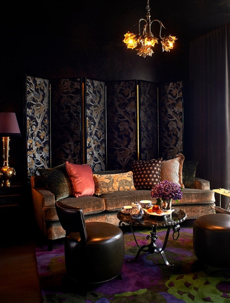 Jewel-box sitting room with a chinoiserie screen and dark velvet sofa at The Mandrake Hotel
