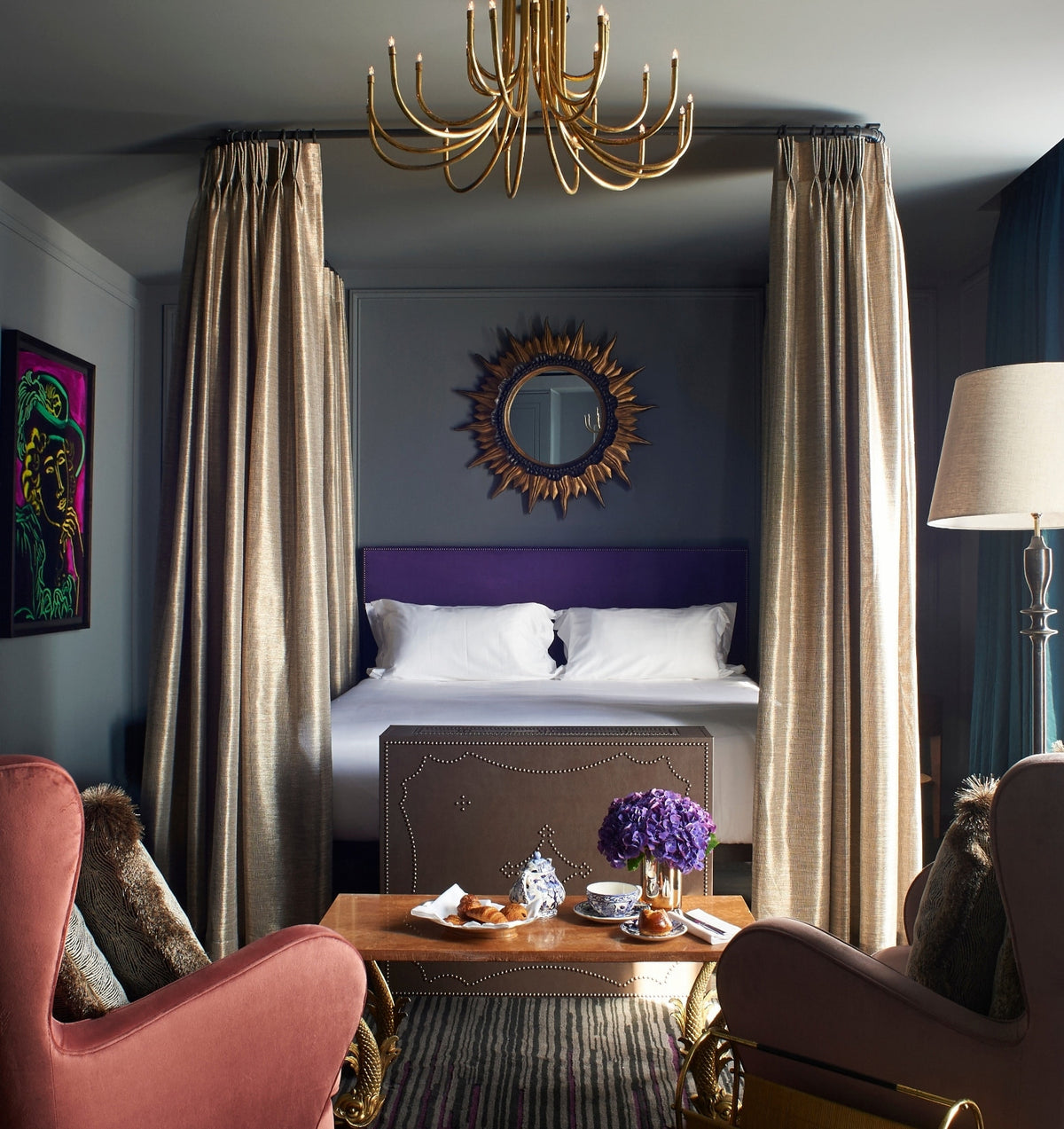 Canopied bedroom with a purple velvet headboard and gold drapery at The Mandrake Hotel