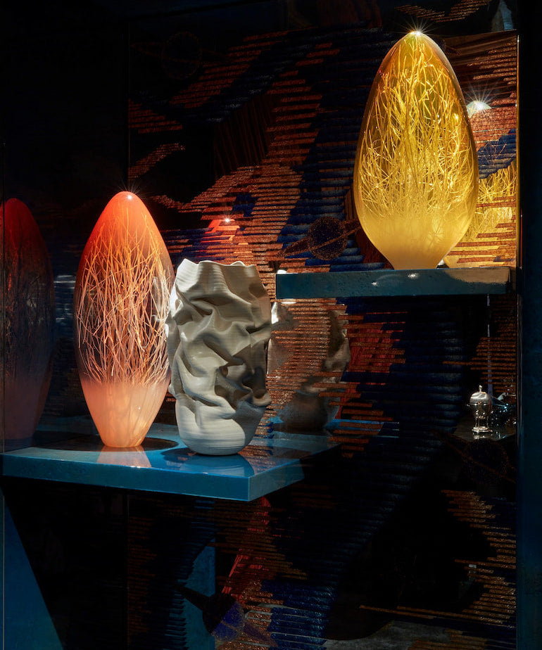 Orange and gold glass sculptures with a rippled white vase in the Home Bar at WOW!house 2023