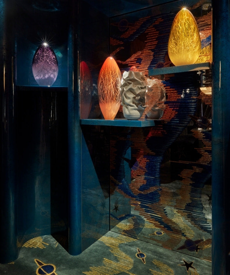 Glowing glass eggs in a lacquered blue alcove with a celestial carpet at WOW!house 2023