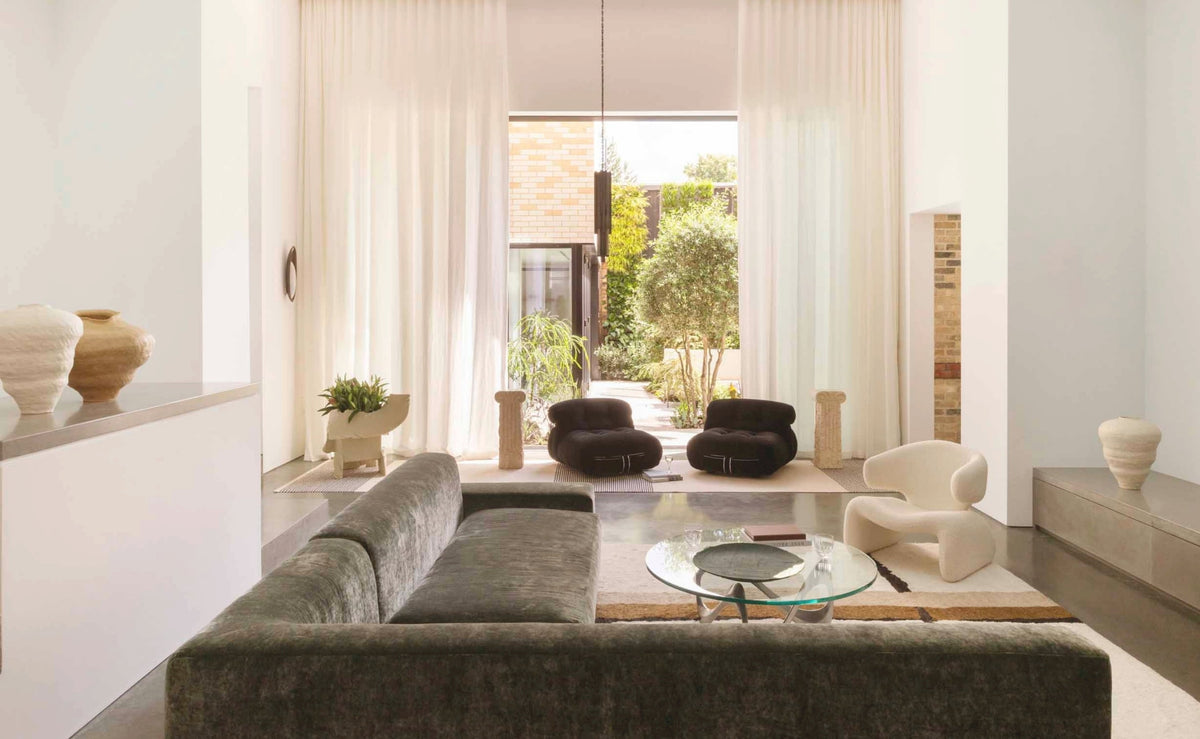 Double-height living room with a sage velvet sofa opening to a courtyard in the North London warehouse