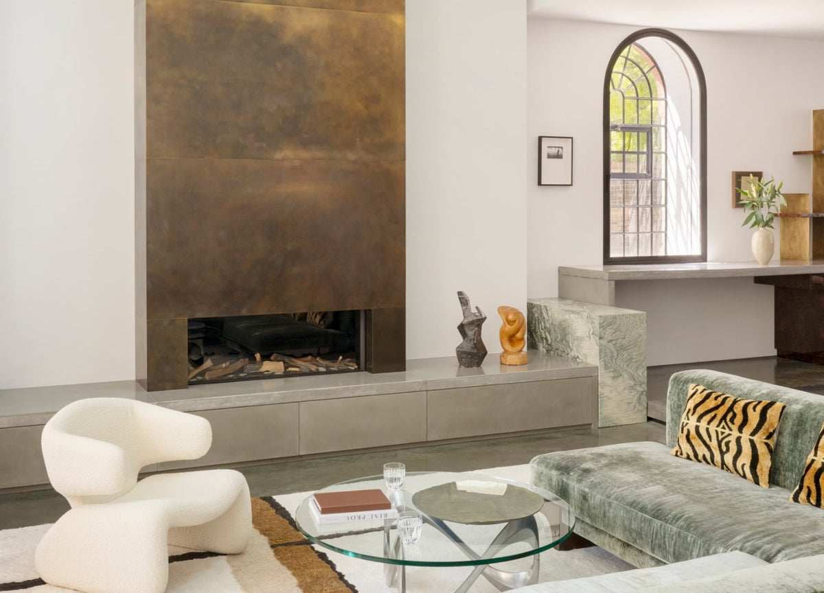 Living room with a floor-to-ceiling patinated brass fireplace in the North London warehouse by Tala Fustok Studio