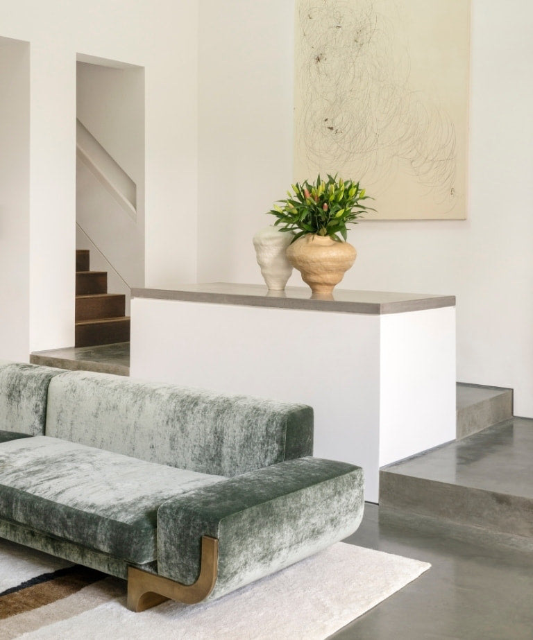 Sage velvet sofa beside a concrete island and abstract line drawing in the North London warehouse