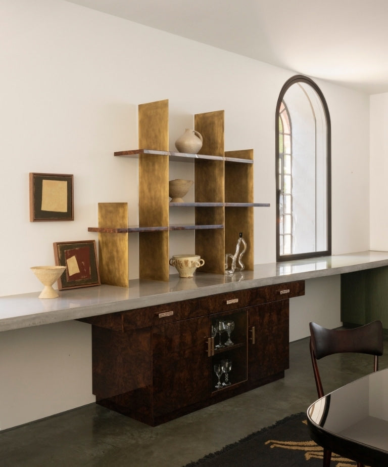Concrete kitchen counter with a brass shelving unit and burl-wood sideboard in the North London warehouse