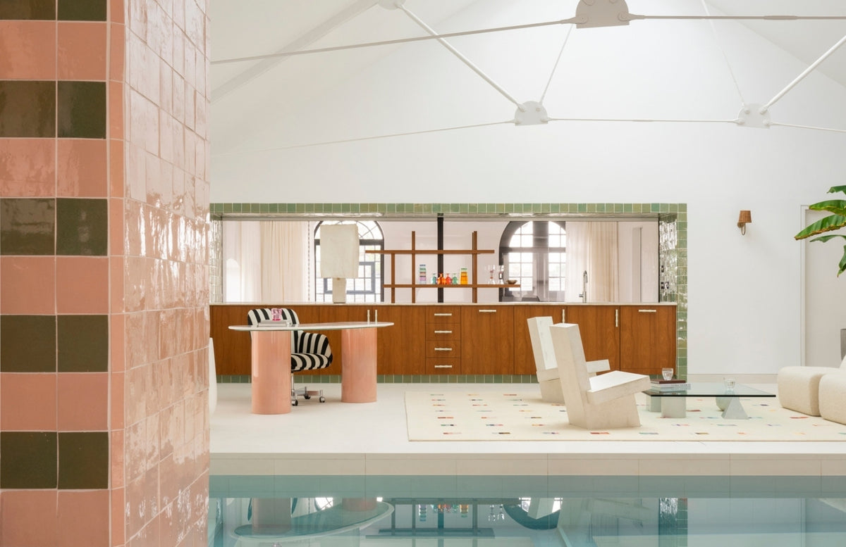 Indoor pool opening to a lounge with pink-and-green tiled columns in the North London warehouse