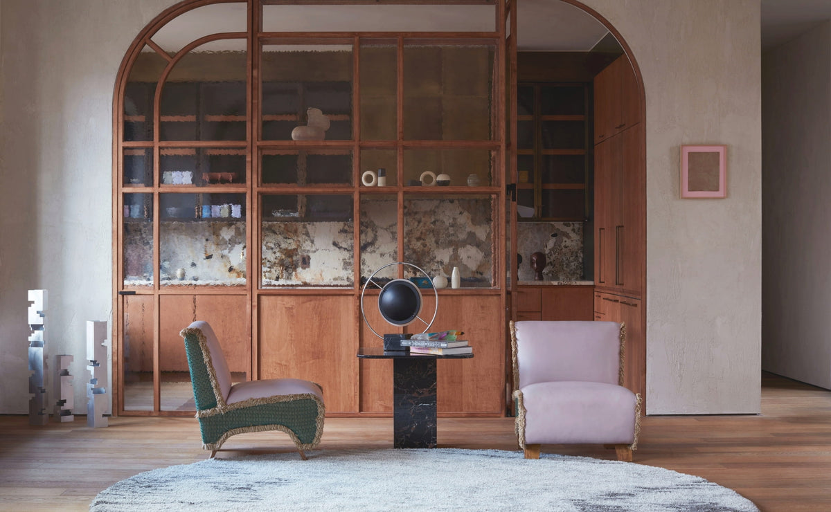 Living room with lavender fringed chairs and an arched wood-and-glass partition in the New York SoHo apartment