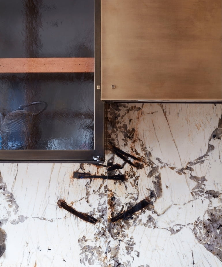Rippled-glass and brass cabinetry against a lightning-veined stone backsplash in the New York SoHo apartment