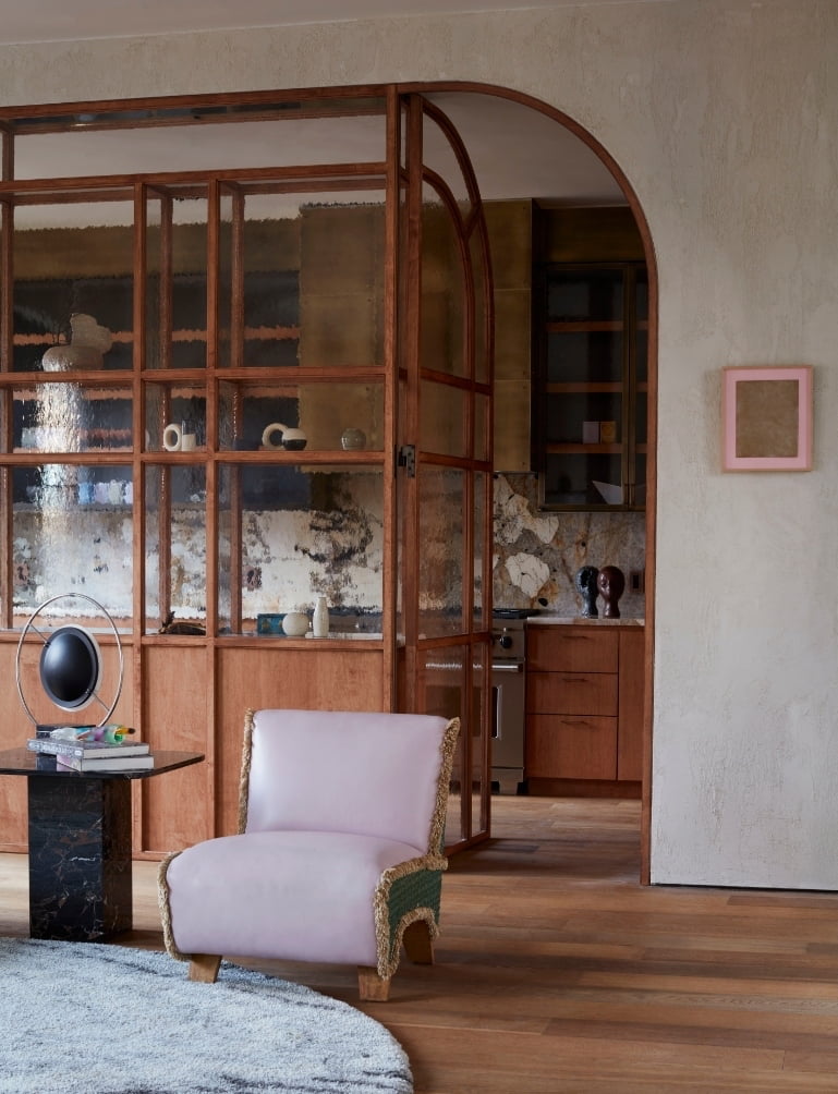 Lavender lounge chair facing an arched wood partition into the kitchen in the New York SoHo apartment