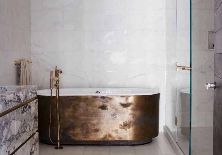 Patinated bronze freestanding bathtub with brass fittings in the New York SoHo apartment by Tala Fustok Studio