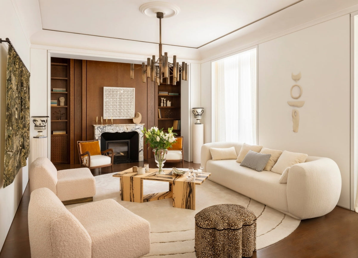 Living room with a curved cream sofa, marble fireplace, and wood-paneled bookshelves in the Paris 16th apartment