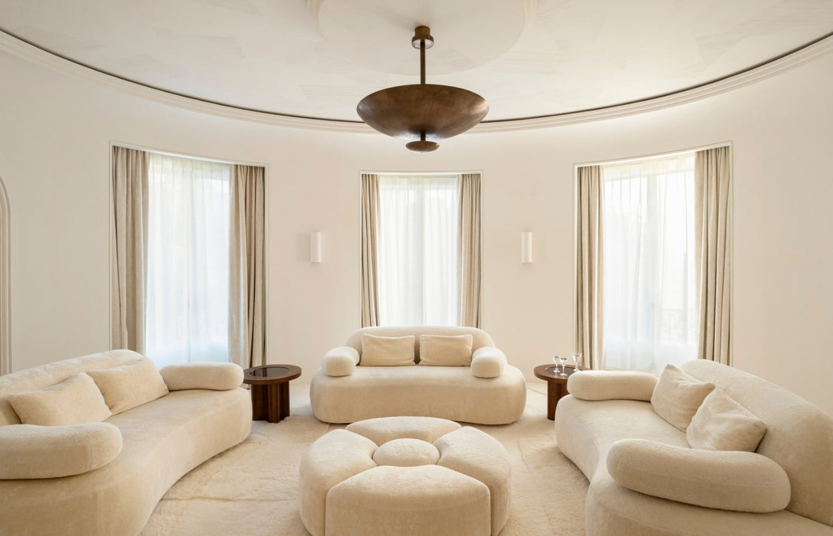 Circular sitting room with cream bouclé sofas and a flower-shaped ottoman in the Paris 16th apartment