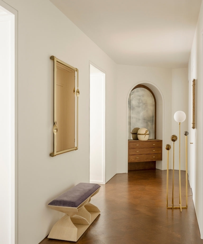 White hallway with herringbone floors, a purple velvet bench, and an arched niche in the Paris 16th apartment
