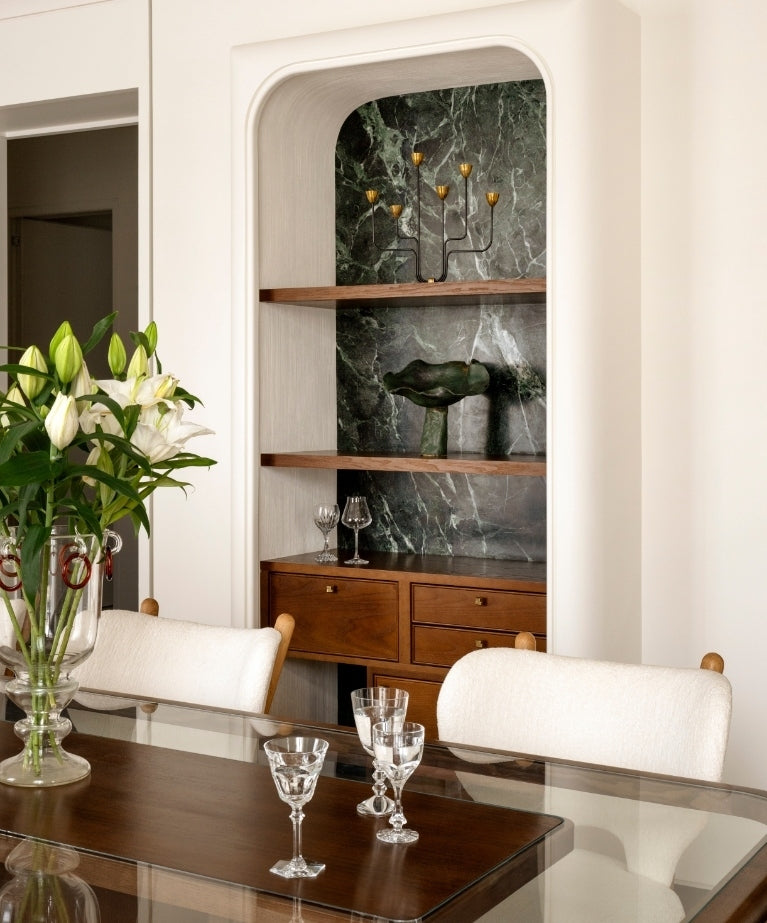 Dining area with an arched green-marble alcove and a glass-topped table in the Paris 16th apartment