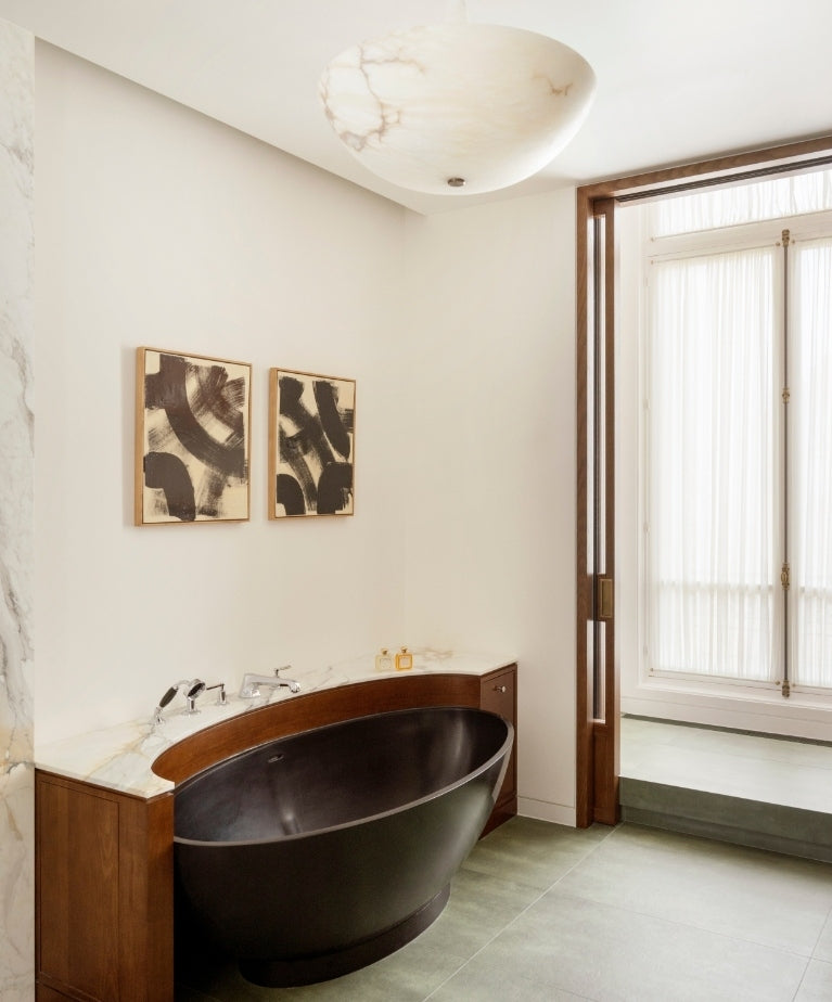 Bathroom with a matte black oval tub set into a dark wood vanity in the Paris 16th apartment