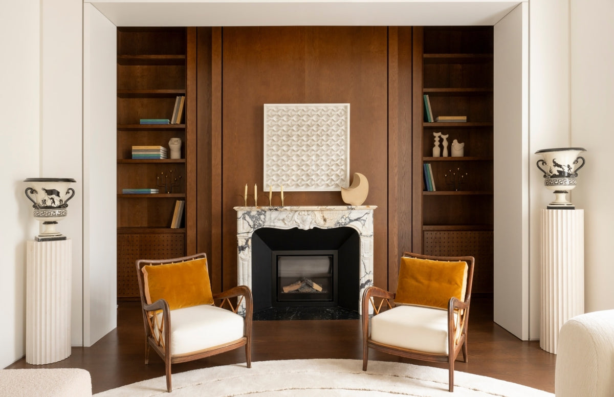 Marble fireplace with wood paneling and mid-century chairs in the Paris 16th apartment by Tala Fustok Studio