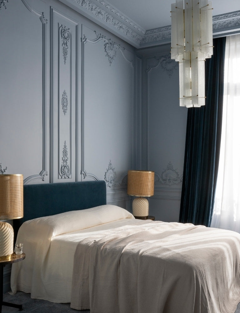 Powder-blue bedroom with a teal velvet headboard and glass chandelier in the Paris 16th apartment