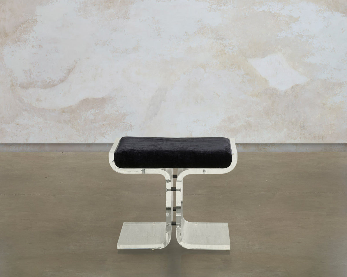 Front view of the Trace stool, with a black velvet seat on a transparent Lucite base
