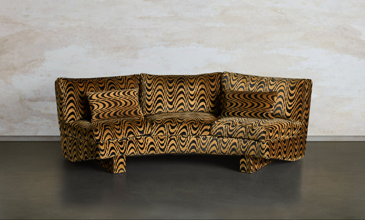 Tripnotic curved three-seater sofa by Tala Fustok Studio, upholstered in gold and black wavy fabric