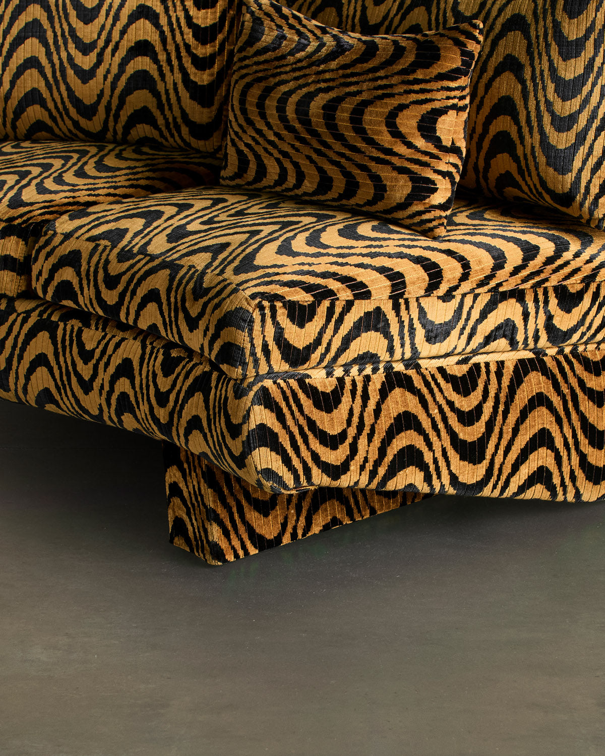 Detail of Tripnotic’s gold and black wavy upholstery across the seat, arm, and cushion