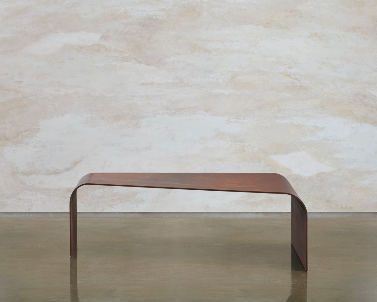 Side view of the Perception coffee table, showing its low corten steel arch and tapered top