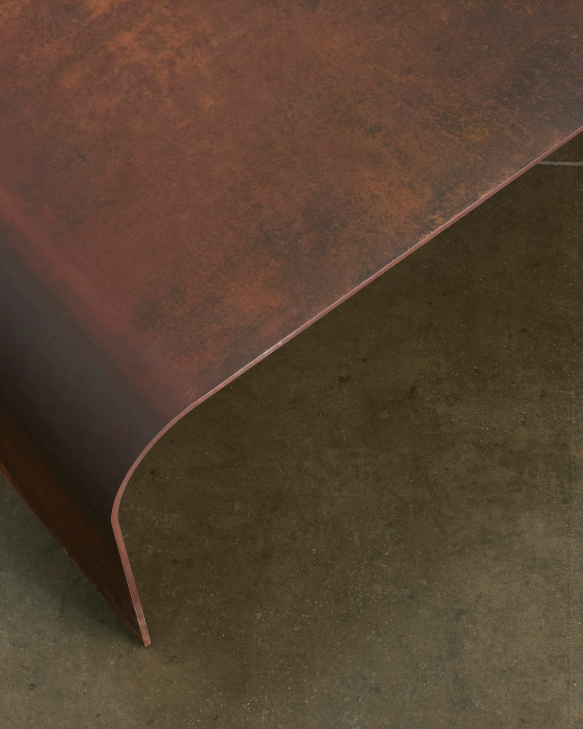 Detail of Perception’s weathered corten edge as it curves toward the concrete floor
